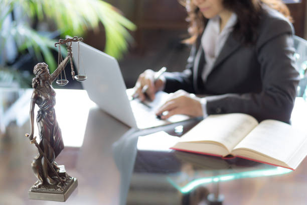 cabinet d’avocat. statue de la justice avec des échelles et avocat travaillant sur un ordinateur portable. notion juridique de droit, de conseils et de justice - female photos et images de collection