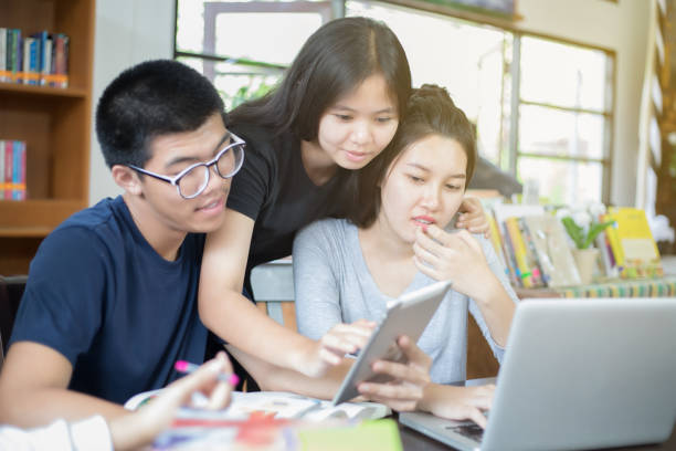 istock Asian Group of students sharing with the ideas for working on the campus lawn 695204652