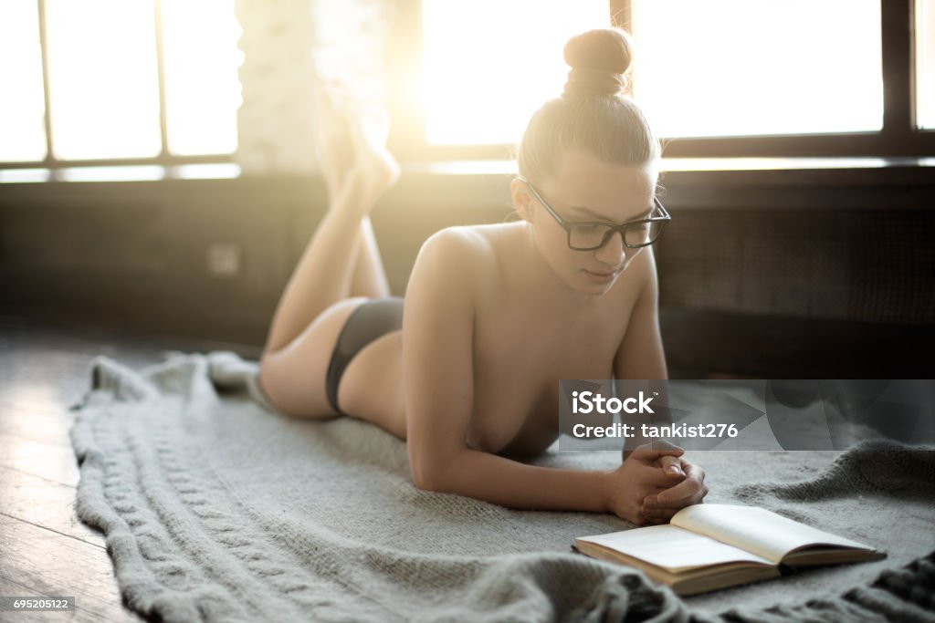 belleza sexy joven mujer mentira Casa en piso y leer libro - Foto de stock de Cama libre de derechos