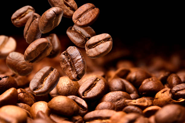 istock Falling coffee beans. Dark background with copy space, close-up 695216168