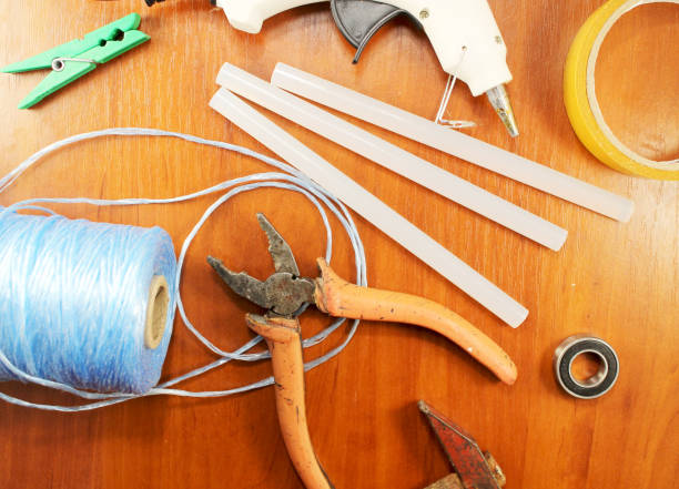 istock Woodworking workshop. lose-up on top of the tools for creating DIY or working with tree. Glue gun, silicone rods, pliers, nylon thread, scissors and colored pencils in the background of wood 695219300