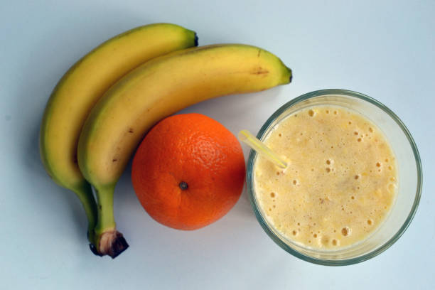 A composition of bananas and orange and a glass with smoothies stock photo