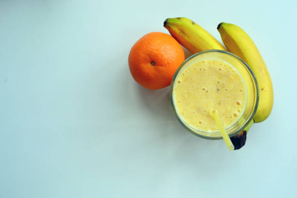 A composition of bananas and orange and a glass with smoothies stock photo