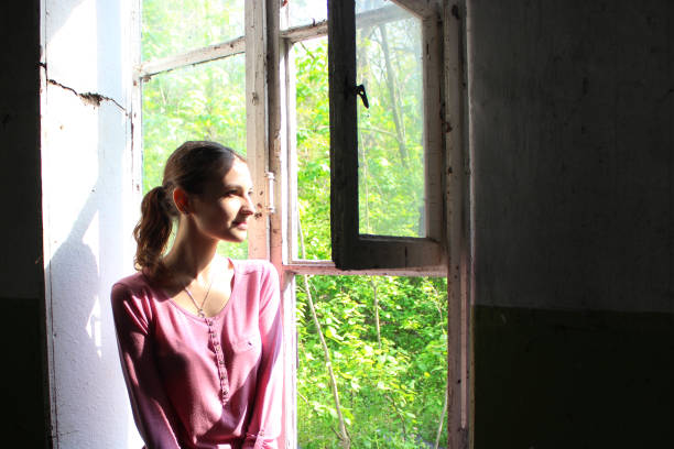 istock Woman looking through the old window 695241314