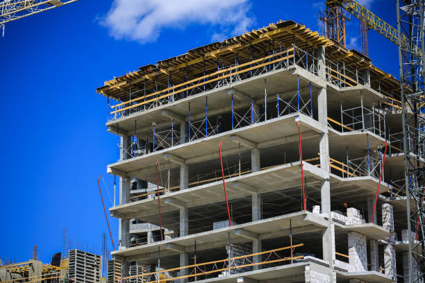 istock Construction concept. A new building under construction against the sky. Blue background. New urban city. Machinery, cranes and builders on scaffolding. Heavy industry and safety at work 695243726