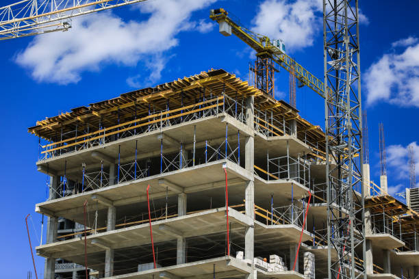 istock Construction concept. A new building under construction against the sky. Blue background. New urban city. Machinery, cranes and builders on scaffolding. Heavy industry and safety at work 695249366