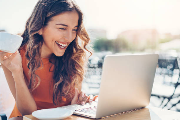 istock Young woman with laptop in sidewalk cafe 695263322