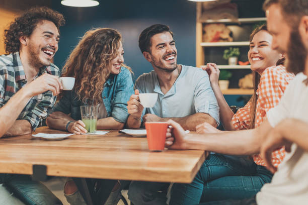 istock Group of young people sitting and talking in cafe 695263342