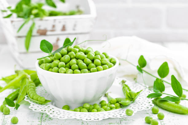 istock Green peas with leaves on white background 695264270