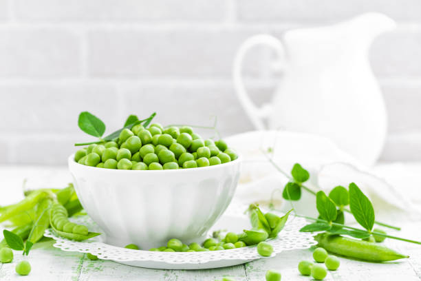 istock Green peas with leaves on white background 695264274