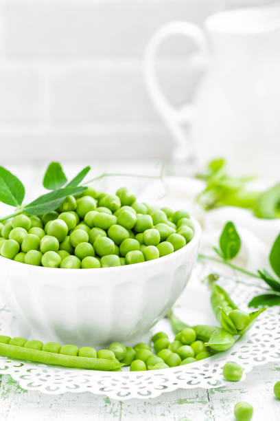 istock Green peas with leaves on white background 695264284