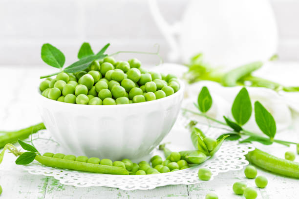 istock Green peas with leaves on white background 695264316