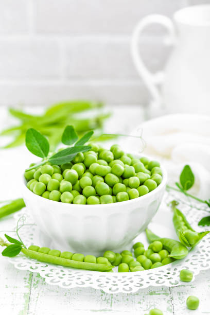 istock Green peas with leaves on white background 695264318