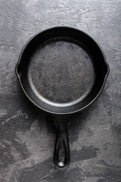 istock Empty cast iron frying pan on dark grey culinary background, view from above 695264882