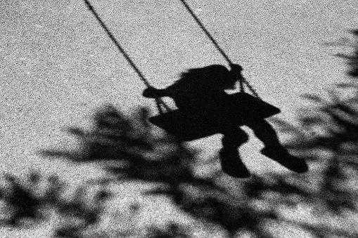 Bluury shadows of little giirl on a swing and a tree branch