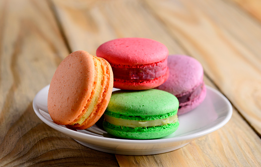 colorful macaroons on porcelain plate on wooden table