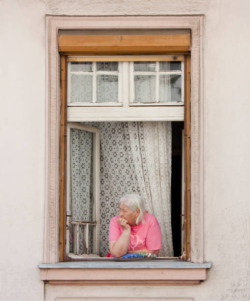 Fluminimaggiore, Sardinia, Italy, August, 20th 2007: In the small town, an old woman looks through the window of his house to see what happens in the village street. In the streets nothing ever happens.