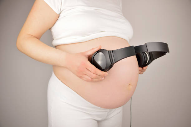 A pregnant woman playing music to her baby with headphones