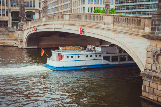 White ship passing under the Friedrichsbrucke bridge on Spree river in rainy day.