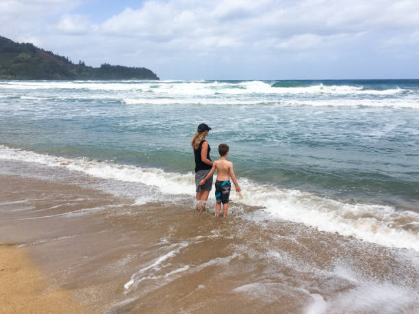 istock mother and son play together in the waves 695294028