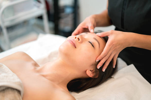 hermosa mujer asiática recibiendo un masaje facial en el spa - tratamiento de spa fotografías e imágenes de stock