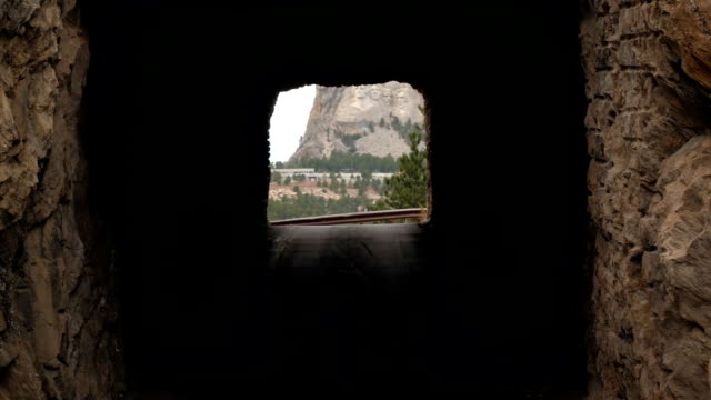 SLOW MOTION: Scenic view of narrow rock tunnel framing Mt. Rushmore in distance