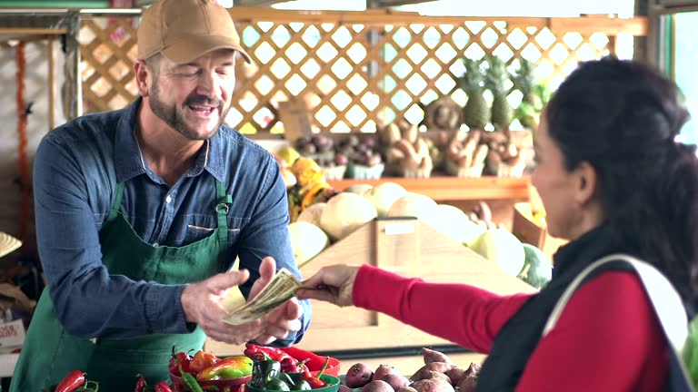 Customer at produce stand paying cash for tomatoes