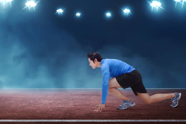istock Young asian runner man kneeling ready in start position 695316404