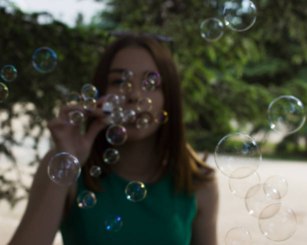 istock Young pretty girl blows bubbles, outdoor 695325782