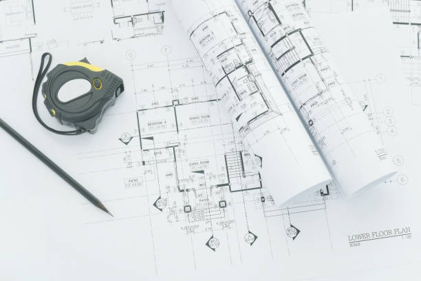 istock architects workplace - architectural blueprints with measuring tape, safety helmet and tools on table. top view 695334522