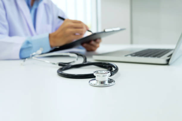 istock Doctor working with laptop computer and writing on paperwork. Hospital background. 695356876