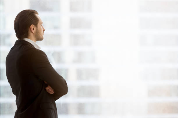 istock Businessman dreamily looks in window at office 695358892