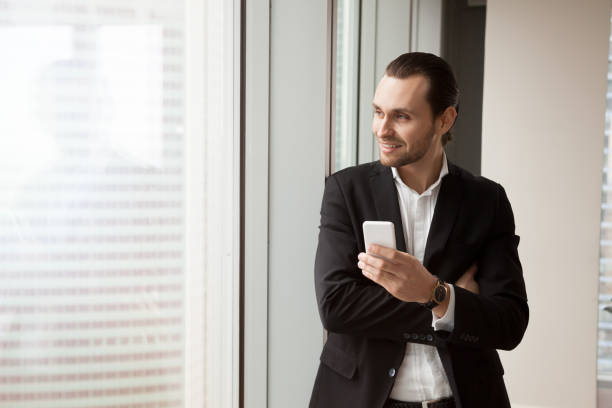 istock Successful businessman standing with cellphone 695358894
