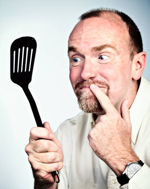 istock Smiling man looking at kichen egg turner, finger to lips 695381166