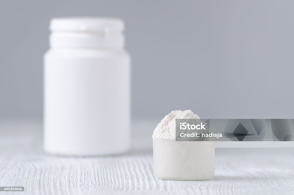 a spoon with white powder and a bottle on gray, selective focus a spoon with white powder and a bottle on gray background Ground - Culinary Stock Photo