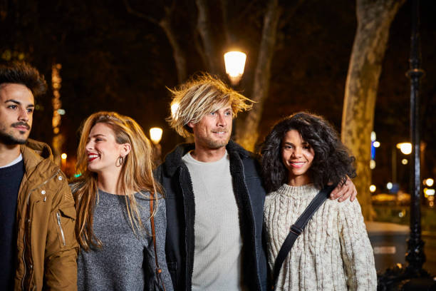 istock Smiling friends walking in city at night 695407668
