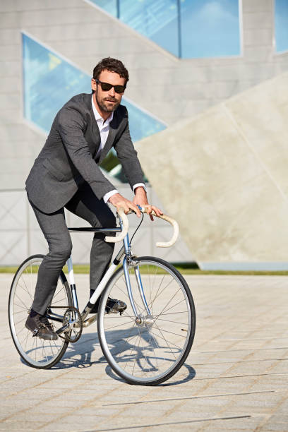 istock Full length of executive riding bicycle on street 695407912