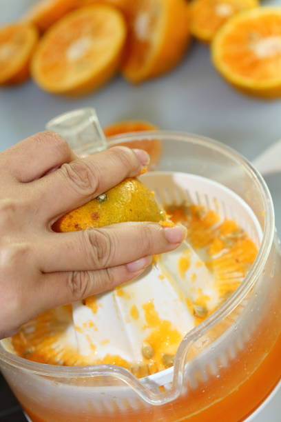 istock orange fruit squeezed with woman hand in juicer machine, orange juice 695414772