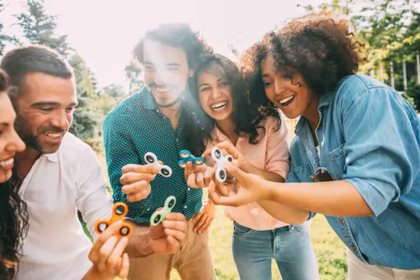 Friends playing with fidget spinners outdoors.