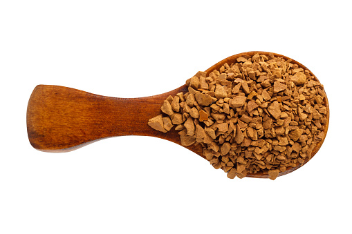 Granules of instant coffee in a wooden spoon isolated. Top view.