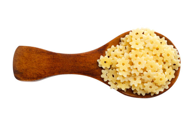 istock Pasta in wooden spoon isolated on white. Top view. 695437788