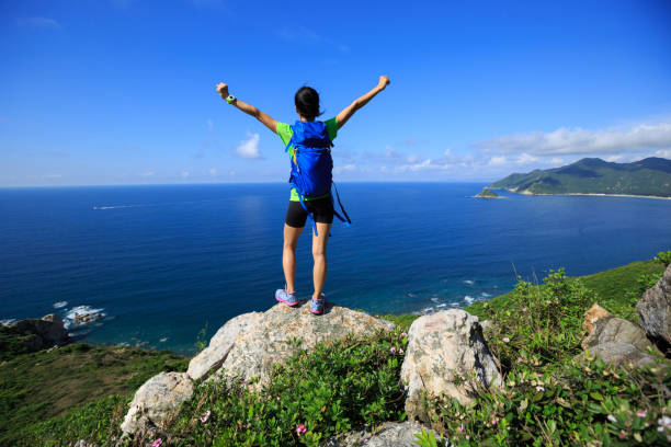 istock successful woman backpacker open arms on seaside mountain peak 695442118
