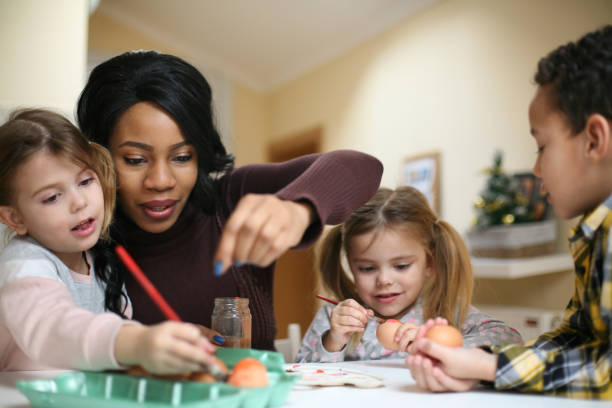 femme avec trois enfants. une femme afro-américaine avec trois enfants se préparent pour pâques. - nurse photos et images de collection