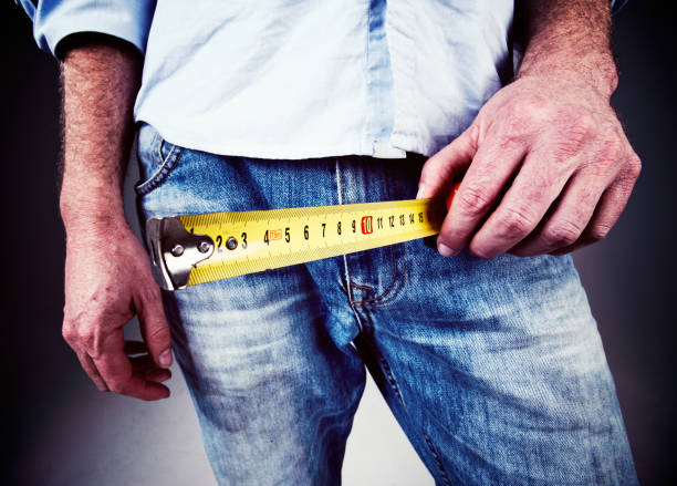 Does he measure up? Man measuring his pelvic area Man holds tape measure by his pelvis, with exaggerated perspective. Does he measure up? penis photos stock pictures, royalty-free photos & images