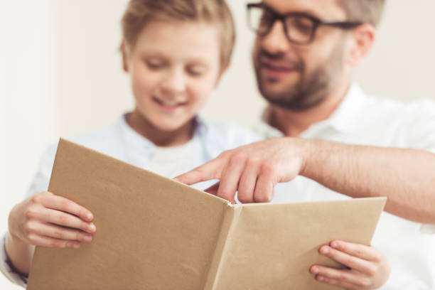 istock little son with father reading book at home together 695455446