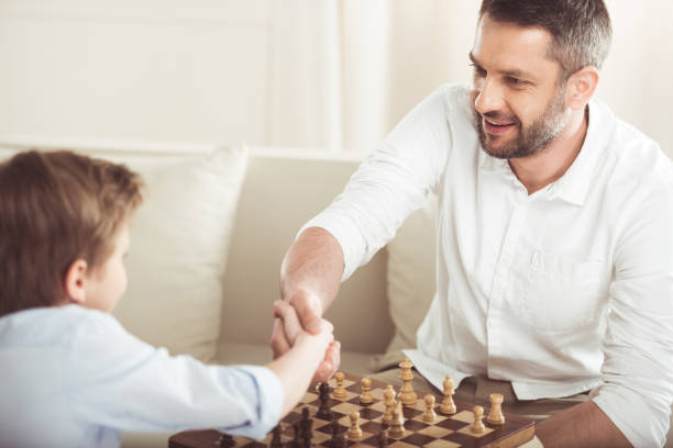 istock father and son shaking hands after playing chess board game 695455922