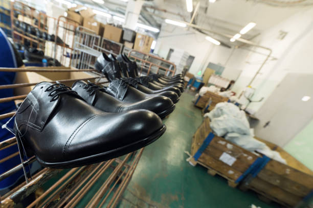 A long line of new black shiny shoes. Shoe factory, finished goods warehouse.