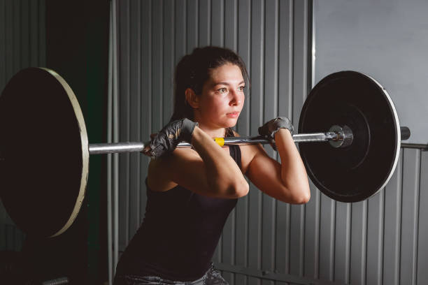 Strong woman lifting barbell as a part of exercise routine stock photo