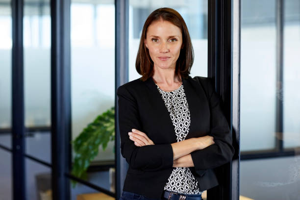 istock Female executive with arms crossed leaning on wall 695461698