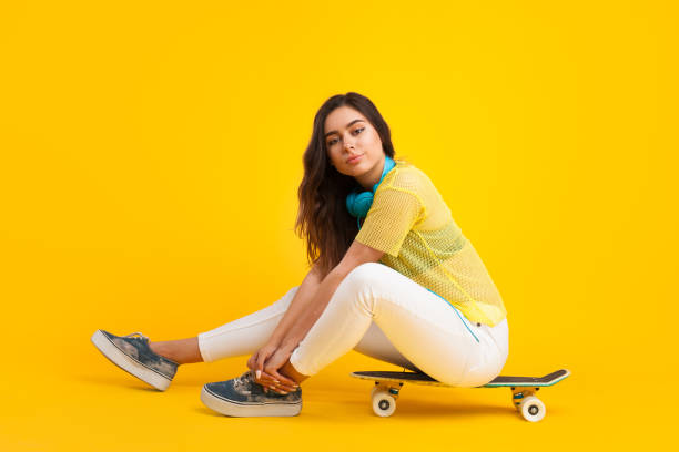 istock Young woman sitting on skateboard 695461782